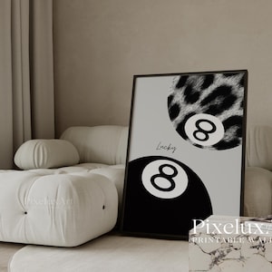 K&ouml;nnte beinhalten: Schwarz gerahmtes Wandbild mit zwei Billardkugeln mit der Nummer 8. Eine Kugel ist schwarz, die andere hat ein Leopardenmuster. Das Wort "Lucky" ist kursiv geschrieben. Der Hintergrund ist hellgrau.