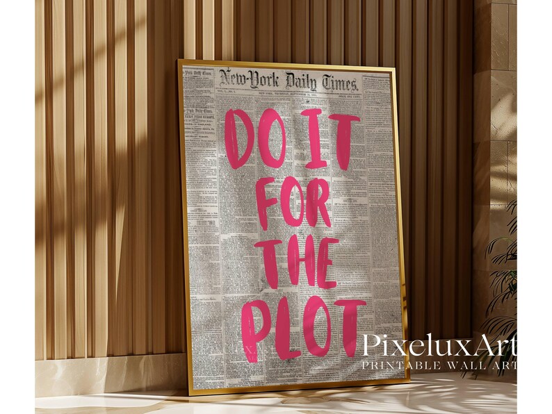 Puede incluir: Impresi&oacute;n enmarcada con la frase "DO IT FOR THE PLOT" en letras rosa brillante. El fondo es una impresi&oacute;n de peri&oacute;dico vintage. El marco dorado contrasta con el texto rosa. La impresi&oacute;n est&aacute; apoyada contra una pared de madera.