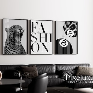 K&ouml;nnte beinhalten: Drei gerahmte Schwarz-Wei&szlig;-Drucke. Sie zeigen einen br&uuml;llenden Leoparden, das Wort "FASHION" in fetten Buchstaben und eine Billardkugel mit der Nummer 8 und Leopardenmuster. Sie sind &uuml;ber einem schwarzen Ledersofa ausgestellt.