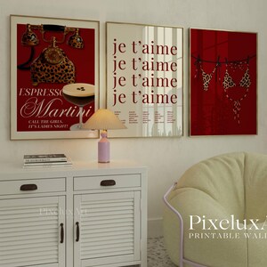 May include: Three framed wall art prints. The left print features a red background with a leopard print telephone and a martini glass. The middle print has the words "je t'aime" repeated. The right print shows a leopard print bikini. A pink lamp sits on a white cabinet.