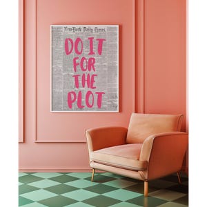 Puede incluir: Una impresi&oacute;n enmarcada con el texto "DO IT FOR THE PLOT" en letras de color rosa brillante. La impresi&oacute;n est&aacute; sobre un fondo de peri&oacute;dico gris. Debajo de la impresi&oacute;n hay un sill&oacute;n color melocot&oacute;n, y el suelo tiene un patr&oacute;n de cuadros verdes y blancos.