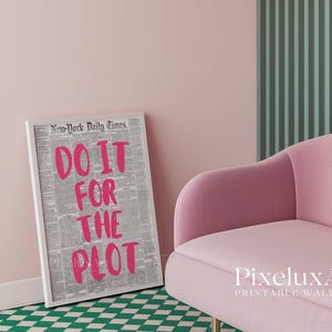 Puede incluir: Un estampado enmarcado con el texto "DO IT FOR THE PLOT" en rosa brillante, sobre un fondo de peri&oacute;dico. El estampado est&aacute; en un marco blanco y se apoya en una pared rosa. Tambi&eacute;n se ven un sill&oacute;n rosa y un suelo a cuadros verdes y blancos.
