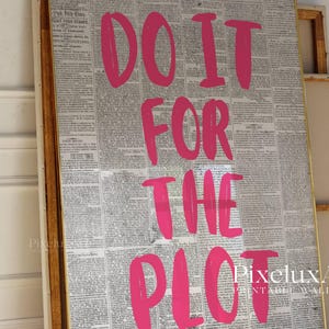 Puede incluir: Arte mural enmarcado con un fondo de peri&oacute;dico vintage y la frase "DO IT FOR THE PLOT" en letras rosa brillante. La obra de arte se presenta en un marco de madera.