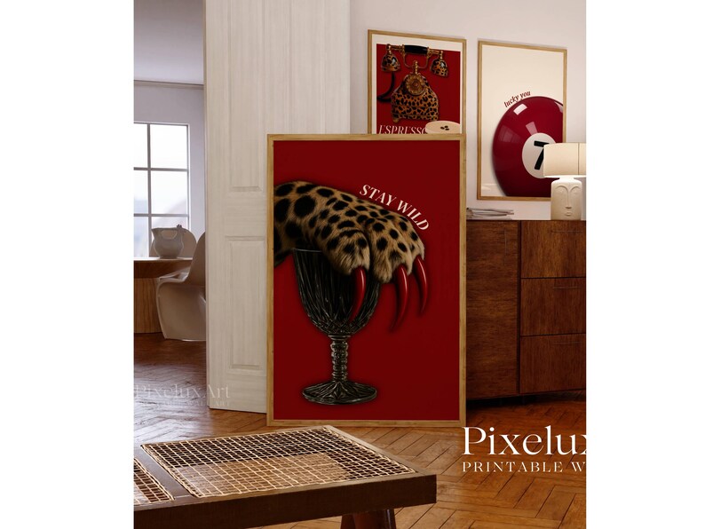 May include: A framed print with a red background features a leopard paw with long red claws emerging from a dark glass. The words "STAY WILD" are printed in white. Other framed prints are visible.
