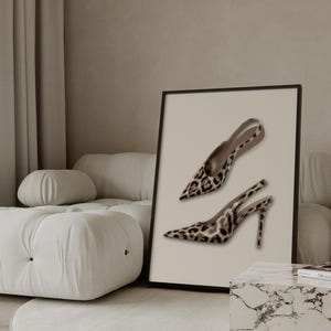 May include: A framed print featuring two high-heeled shoes with a leopard print design. The shoes have pointed toes and thin straps. The print is displayed on a neutral background, adding a touch of elegance to the decor.