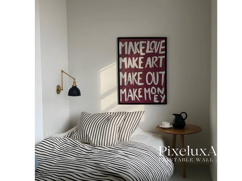 Puede incluir: Una l&aacute;mina de arte mural rectangular en un marco negro con el texto blanco "MAKE LOVE MAKE ART MAKE OUT MAKE MONEY" sobre un fondo magenta oscuro. La l&aacute;mina se muestra en una pared blanca sobre una cama con ropa de cama a rayas blancas y negras.