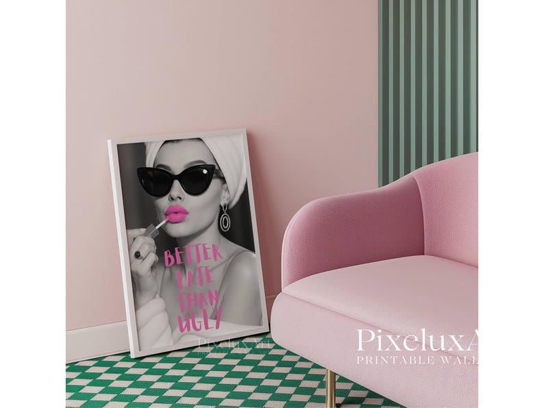 May include: Black and white framed print featuring a woman applying pink lipstick, wearing sunglasses and a headscarf. The text "Better Late Than Ugly" is displayed in pink. A pink velvet chair and a green and white checkered floor are also visible.