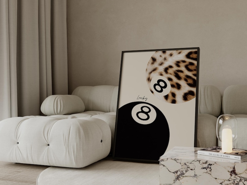 May include: Framed art print featuring a black eight ball and a leopard print eight ball. The word "Lucky" is written in cursive between the two eight balls. The print is displayed on a neutral background.