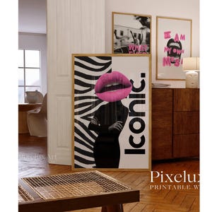 May include: A framed art print featuring a woman's silhouette with a pink lip design and the word "Iconic." The background has a zebra stripe pattern. Two other framed prints are visible in the background.