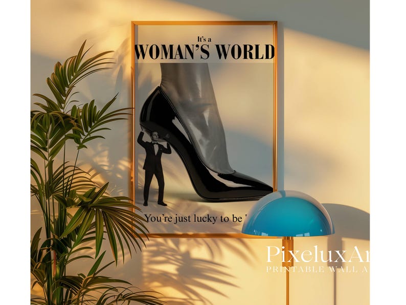 May include: Framed print with the text "It's a Woman's World" and a black high-heeled shoe. A small figure in a suit appears to be holding up the shoe. The text "You're just lucky to be" is also visible.