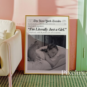 May include: A framed print with a gold border, featuring a black and white image of a woman sleeping with a cat. The print has text that reads "The New York Trends" and "I'm Literally Just a Girl."
