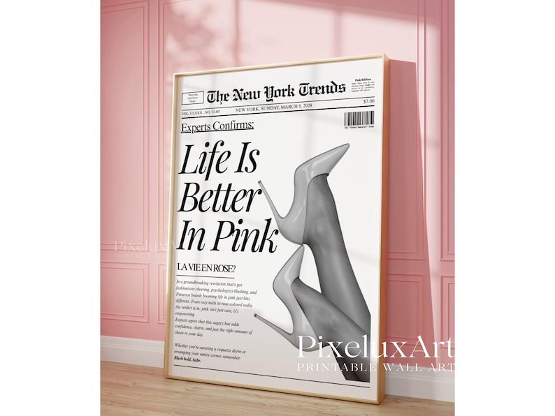 May include: A framed print featuring a newspaper-style design with the headline "Life Is Better In Pink." The image includes a grayscale photo of legs wearing high heels. The print is displayed against a pink wall.