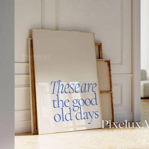 Pode incluir: Uma impressão emoldurada com moldura dourada e fundo branco. A impressão apresenta o texto "These are the good old days" em azul.