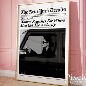 以下が含まれることがあります： 「Woman Searches For Where Men Get The Audacity」という見出しの新聞記事が掲載された、額入りの白黒プリント。サングラスをかけた人物が黒い車を運転している様子が描かれています。新聞のタイトルは「The New York Trends」です。