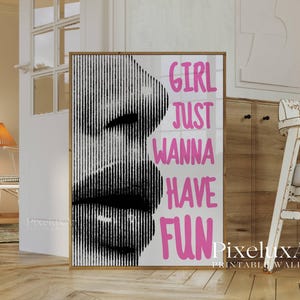 May include: A framed print featuring a black and white image of a face with vertical lines. The words "GIRL JUST WANNA HAVE FUN" are in pink. The print is displayed in a room with wooden floors and a cabinet.