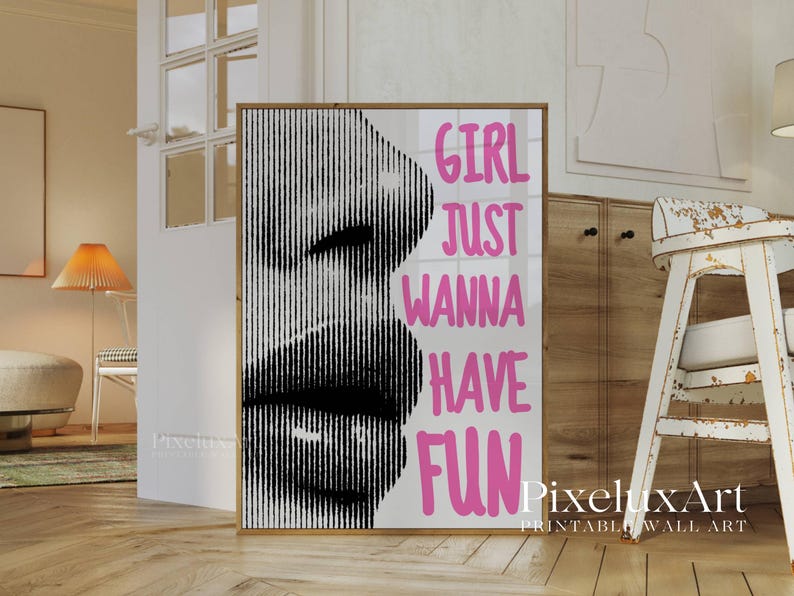 May include: A framed print featuring a black and white image of a face with vertical lines. The words "GIRL JUST WANNA HAVE FUN" are in pink. The print is displayed in a room with wooden floors and a cabinet.