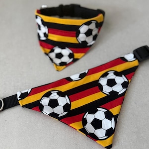 Könnte beinhalten: Ein Hunde-Halsband und ein passendes Bandana-Set. Die Artikel zeigen ein sich wiederholendes Muster von Fußbällen auf einem Hintergrund aus roten, schwarzen und gelben Streifen. Das Halsband hat eine schwarze Schnalle.