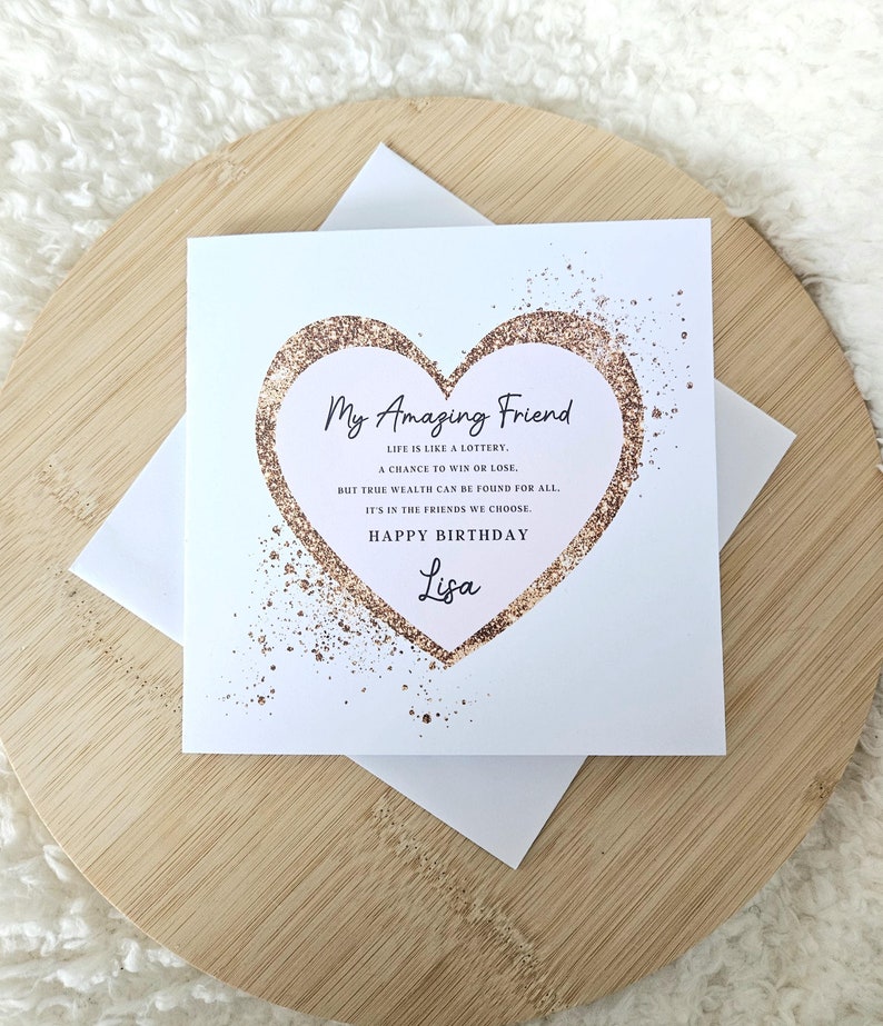 Puede incluir: Una tarjeta blanca con un coraz&oacute;n dorado brillante que dice "Mi incre&iacute;ble amigo" y una cita sobre la amistad. La tarjeta tambi&eacute;n dice "Feliz cumplea&ntilde;os Lisa".