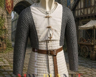 May include: Medieval chainmail armour with a white padded undergarment and a brown leather belt. The chainmail sleeves and shoulders contrast with the lighter fabric. The armour is displayed on a mannequin.
