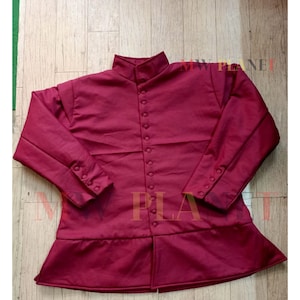 Puede incluir: Una chaqueta acolchada de color burdeos con cuello alto y cierre de botones. La chaqueta tiene mangas largas con puños abotonados y un dobladillo ligeramente acampanado.