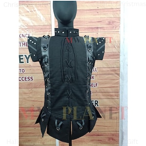 Peut inclure: Vêtement noir sans manches avec un devant à lacets et des bretelles décoratives. Le vêtement a un col montant avec des clous argentés et est fait d'un tissu texturé.