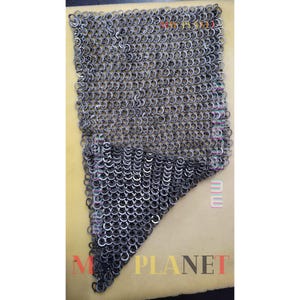 May include: A piece of chainmail armour, made from many small, interlocking metal rings. The chainmail is a silvery-grey colour and is shown against a light tan background. The bottom of the chainmail has a triangular shape.