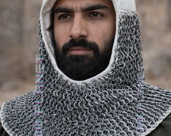 Peut inclure: Une coiffe médiévale en cotte de mailles avec une capuche rembourrée blanche. La cotte de mailles couvre le cou et les épaules, et la capuche encadre le visage. La coiffe fait probablement partie d'une armure.