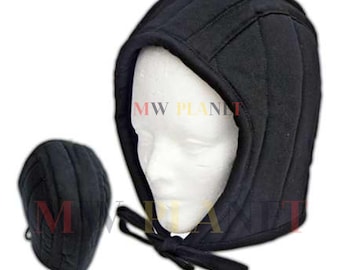 Peut inclure: Cagoule noire rembourrée avec fermeture à nouer, présentée sur une tête de mannequin. Un petit bonnet rembourré noir assorti est également montré. La cagoule et le bonnet semblent être faits d'un tissu matelassé. Le texte "MW PLANET" est visible.
