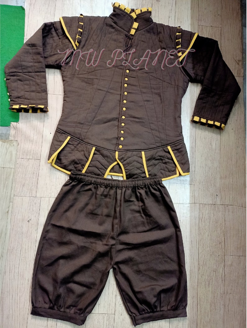 May include: A brown quilted jacket with yellow trim and a matching pair of brown shorts. The jacket has a high collar and a button-up front. The shorts have an elastic waistband.