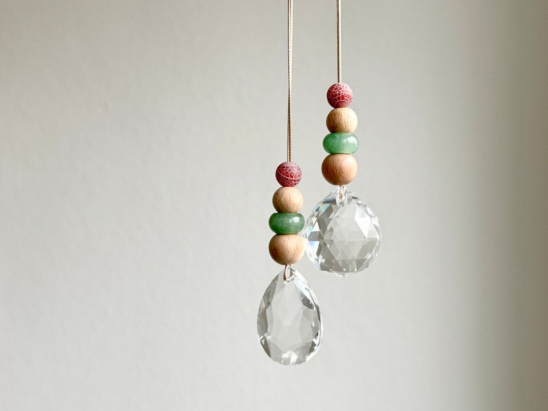 May include: Two crystal suncatchers hanging from strings with wooden beads and green and red beads.