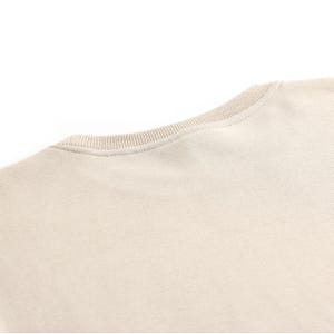 Puede incluir: Una camiseta lisa de color beige claro con cuello redondo.