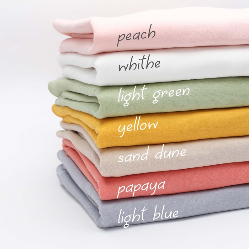 Puede incluir: Un conjunto de muestras de tela en varios colores, incluyendo melocot&oacute;n, blanco, verde claro, amarillo, duna de arena, papaya y azul claro. Las muestras de tela est&aacute;n etiquetadas con sus colores respectivos.