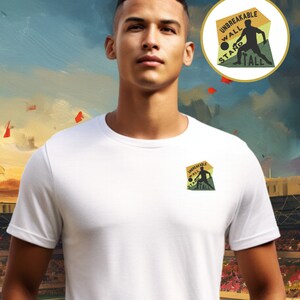 May include: White t-shirt with a yellow, green and orange embroidered patch that says "Unbreakable Wall Stand Tall". The patch features a silhouette of a person playing basketball.