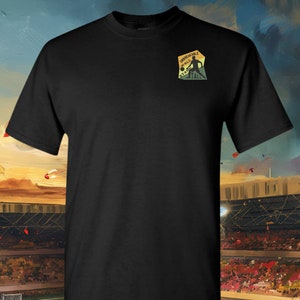 May include: Black t-shirt with a small embroidered patch on the left chest. The patch is yellow, orange, and red with the text "Unbreakable Wall Stand Tall" and a silhouette of a football player.