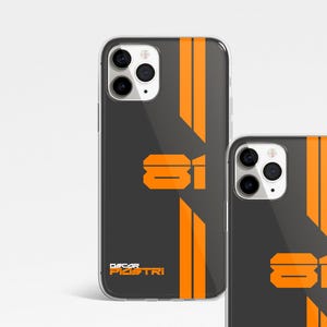 May include: A black phone case with orange stripes and the number "81" printed on it. The text "Oscar Piastri" is printed at the bottom of the case.