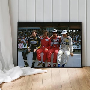 May include: Four men wearing racing suits stand together in front of a crowd. The men are wearing red, blue, and black suits. The man on the left is wearing a black suit with the word "National" on the chest. The man in the middle is wearing a red suit with the word "Denim" on the chest. The man on the right is wearing a blue suit with the word "Denim" on the chest. The men are smiling and looking at the camera.