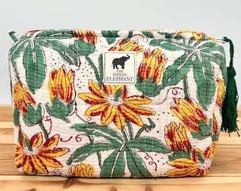 May include: A quilted cosmetic bag with a floral pattern featuring yellow and red flowers, green leaves, and a white background. The bag has a green tassel and a label that says "THE INDIAN ELEPHANT".