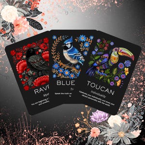 Peut inclure: Trois cartes de tarot noires avec des illustrations d'oiseaux colorés. Les cartes présentent un corbeau, un geai bleu et un toucan, chacun entouré de motifs floraux. Le texte sur les cartes comprend "RAVE", "BLUE" et "TOUCAN", ainsi que des phrases connexes.