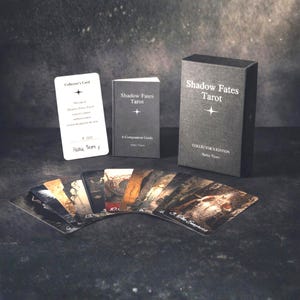Puede incluir: Un juego de tarot Shadow Fates de edición de coleccionista. El conjunto incluye una baraja de cartas ilustradas, una guía y una tarjeta de coleccionista. La caja y la guía son de color gris oscuro con texto blanco. Las cartas están abanicadas.