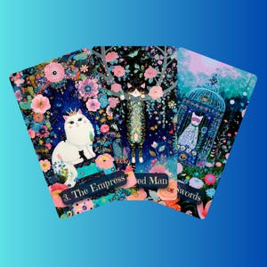 Può includere: Tre carte dei tarocchi con illustrazioni di gatti stravaganti. La carta dell'Imperatrice mostra un gatto bianco con una corona. Le altre carte raffigurano gatti con elementi floreali e decorativi. Sfondo sfumato blu.