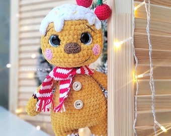 May include: A crocheted gingerbread man toy with a white icing hat, red and white striped scarf, and two red cherries on top. The toy has brown eyes and a brown nose.