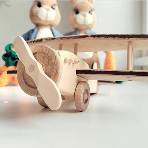 Puede incluir: Un avi&oacute;n de juguete de madera con una h&eacute;lice, alas marrones y un cuerpo marr&oacute;n. El avi&oacute;n est&aacute; sentado sobre una superficie blanca.