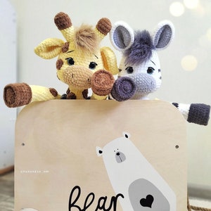 May include: A wooden toy wagon with a white polar bear illustration and the word "bear" printed on the side. Two crocheted stuffed animals, a giraffe and a zebra, are sitting in the wagon.