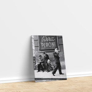 May include: Black and white photograph of a street scene with three men in suits and hats, one walking and two seated. A sign for "Birra Peroni" is visible above them. The image is displayed on a canvas print.