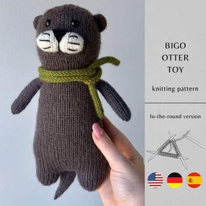 May include: A dark brown knitted otter toy with a green scarf, black eyes, and a white muzzle with black stitched details. The text reads BIGO OTTER TOY, knitting pattern, and In-the-round version, accompanied by a knitting needle illustration.