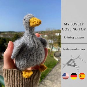 May include: A handmade gray knitted gosling toy with a yellow beak and feet. The text "MY LOVELY GOSLING TOY" and "knitting pattern" are visible. The image also includes the flags of the United States, Germany, and Spain.