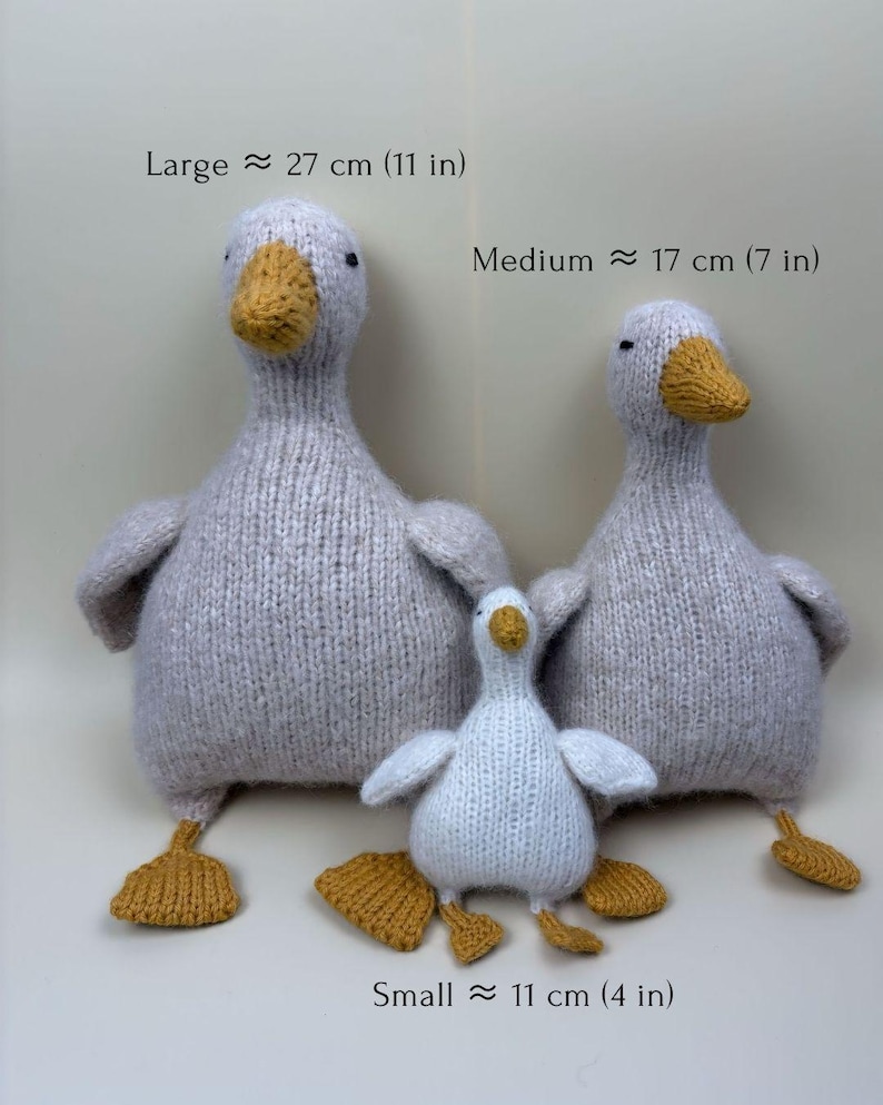 May include: Three knitted goose toys in varying sizes. The largest is approximately 11 inches tall, the medium is 7 inches, and the smallest is 4 inches. Each goose has a gray body, yellow beak and feet, and small black eyes. The text on the image indicates the size of each goose.