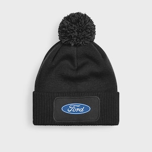 May include: Black knitted beanie hat with a matching pom-pom. The hat has a rectangular patch displaying the Ford logo in blue and white. A winter hat for warmth.