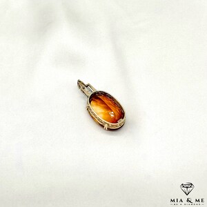 May include: A gold pendant with an oval-shaped amber stone set in a delicate filigree design.