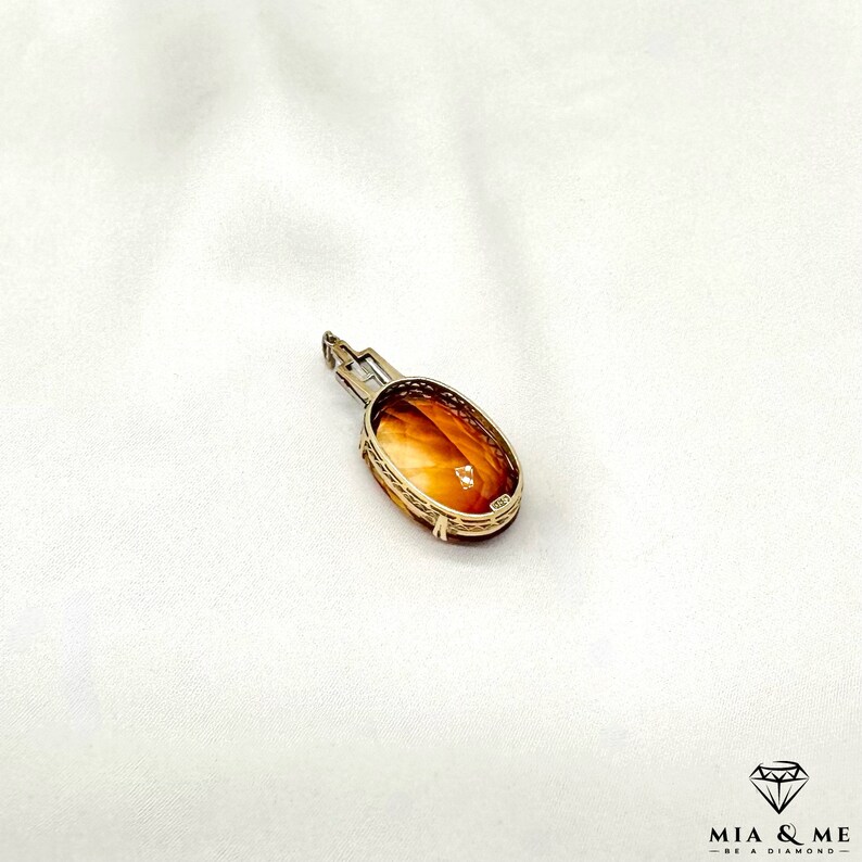 May include: A gold pendant with an oval-shaped amber stone set in a delicate filigree design.